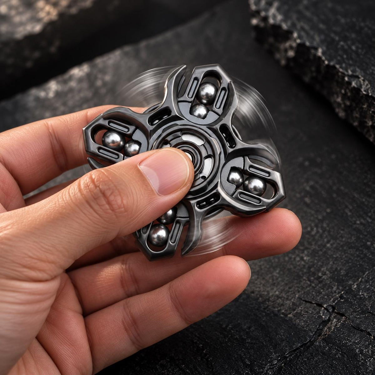 Spinner métallique à quatre branches et billes, tenu entre les doigts