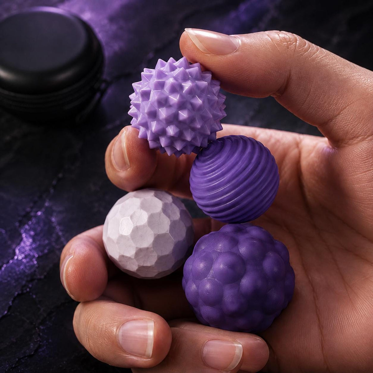 Balles fidget magnétiques texturées : quatre balles violettes texturées tenues en main